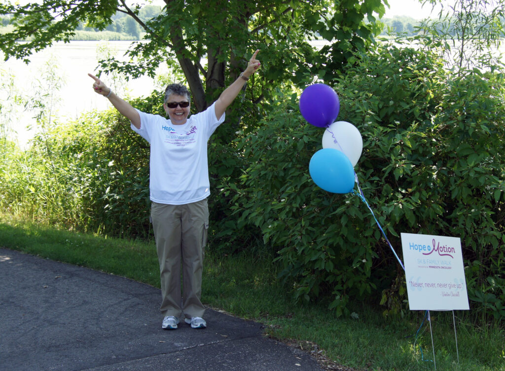 A person standing on the side of a road with balloons.