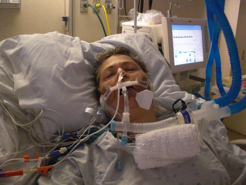 A man in hospital bed with an oxygen mask on.