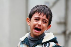 A boy is crying and has his head down.