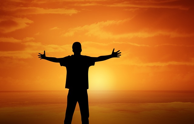 A man standing in front of the ocean at sunset.