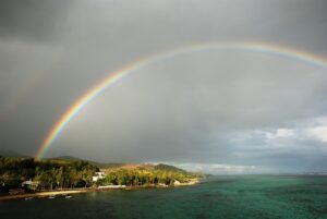 A rainbow over the ocean with a cloudy sky