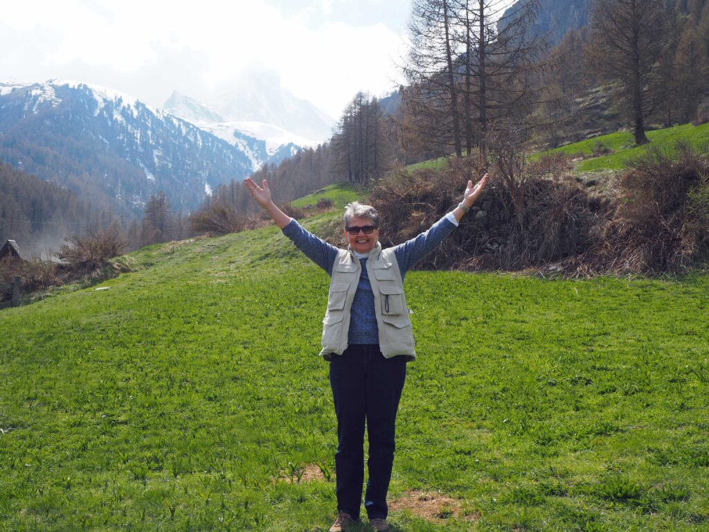 A woman standing in the middle of a field with her arms raised.