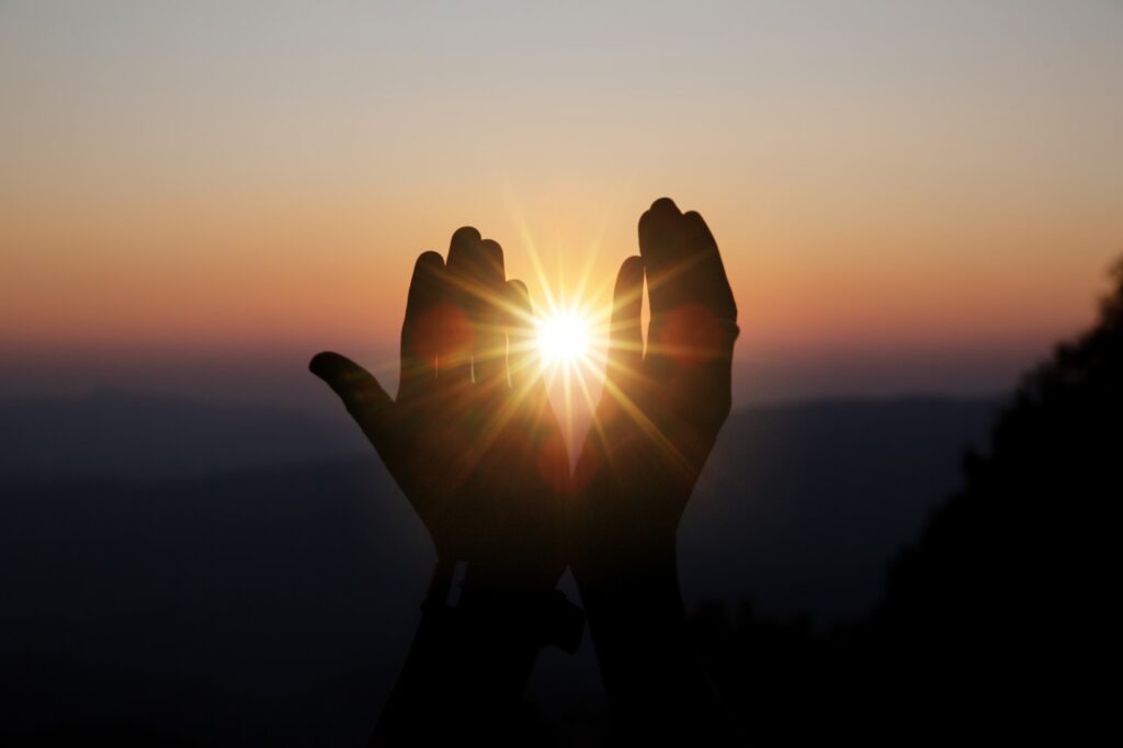 A person holding their hands up to the sun.