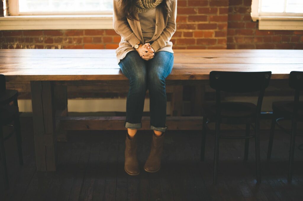 A woman sitting on top of a wooden bench.